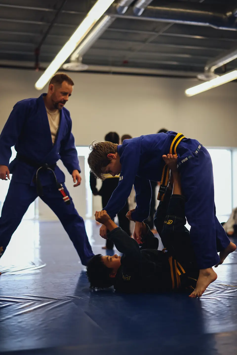 A coach watches closely as youth teammates practise a controlled guard technique