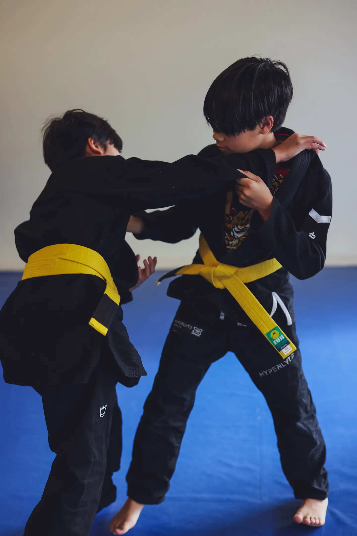 Two youth teammates practise a controlled standing Brazilian Jiu Jitsu grip